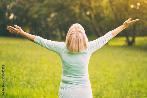 Senior woman enjoys with her arms outstretched in the nature.