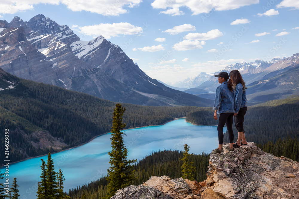 Couple female friends are enjoying the beautiful Canadian Rockies Landscape view during a vibrant sunny summer day. Taken in Peyto Lake, Banff National Park, Alberta, Canada.