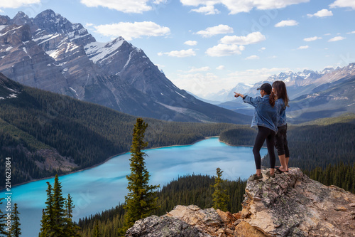 Couple female friends are enjoying the beautiful Canadian Rockies Landscape view during a vibrant sunny summer day. Taken in Peyto Lake, Banff National Park, Alberta, Canada.
