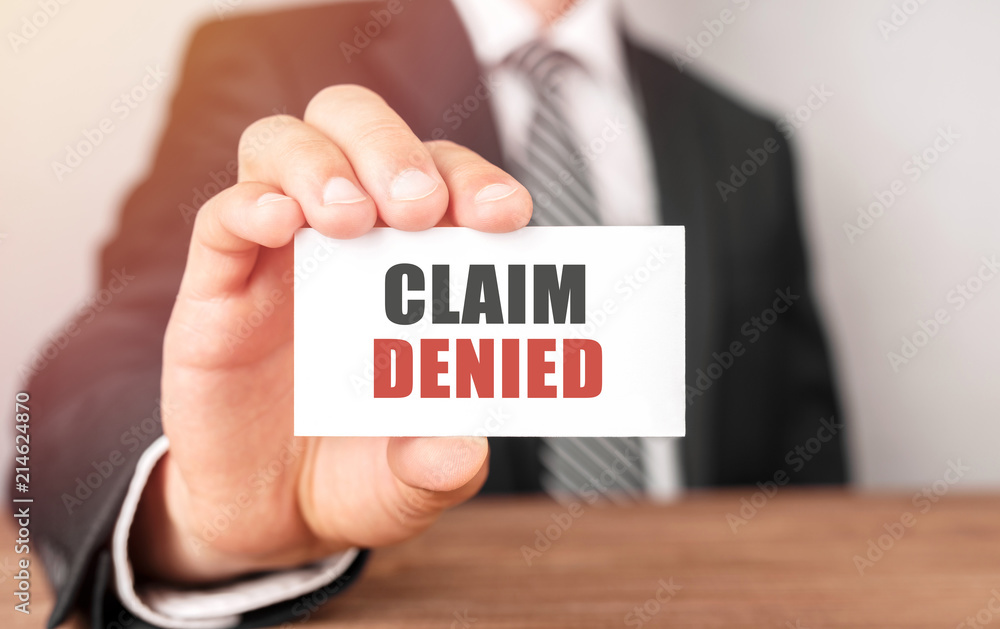 Businessman holding a card with text Claim Denied Businessman holding a card with text Claim Denied
