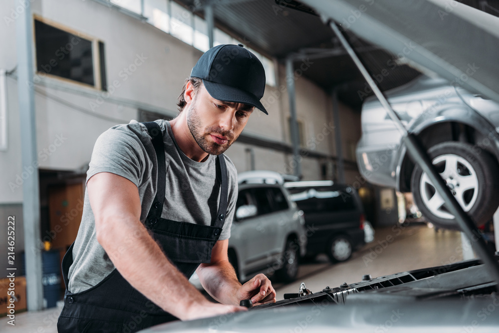 manual worker in overalls repairing car in mechanic shop manual worker in overalls repairing car in mechanic shop
