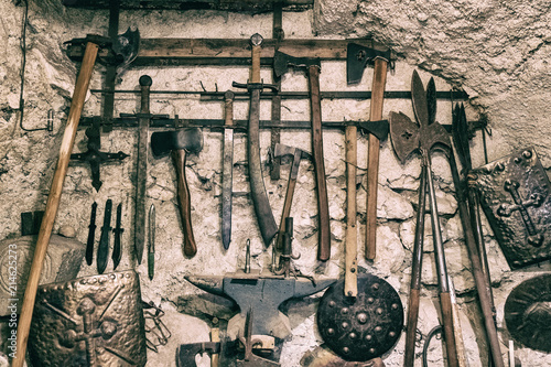 Wallpaper background of ancient medieval weapons hanged on a vintage stone and concrete wall. History of war. photo