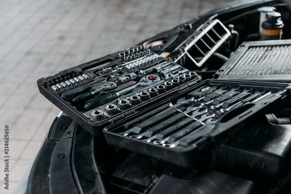 tool case with wrenches and metal nuts lying on opened car hood in workshop tool case with wrenches and metal nuts lying on opened car hood in workshop