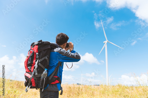 man photographer taking photo of the wind turbines generating electricity Travel Lifestyle adventure concept active vacations into the wild with backpack Travel Lifestyle