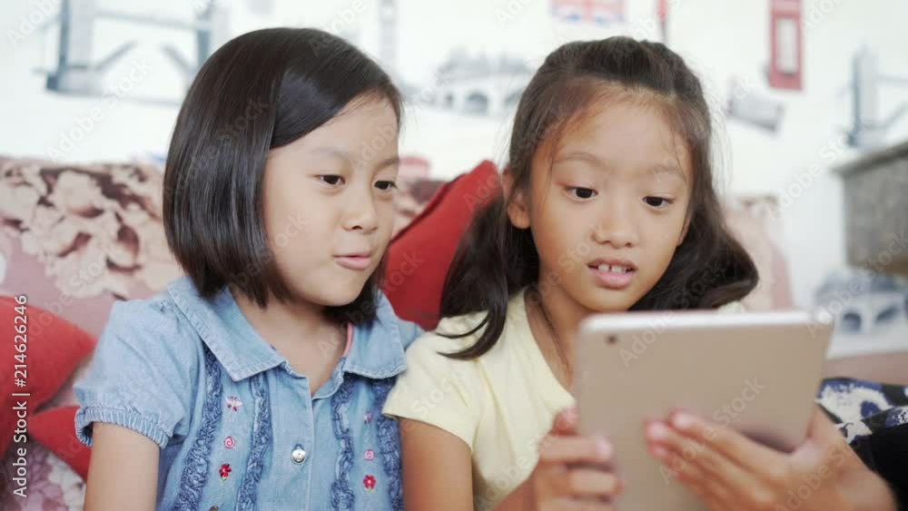 Little girls with friend enjoy playing computer tablet or smartphone Little girls with friend enjoy playing computer tablet or smartphone