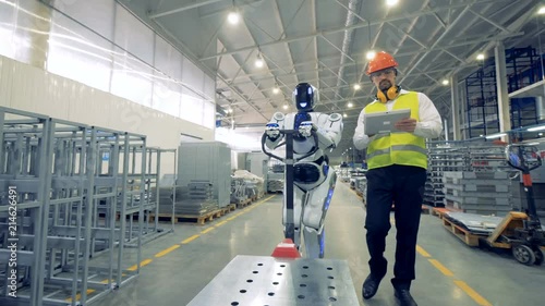 A robot works at a warehouse with a human, close up.