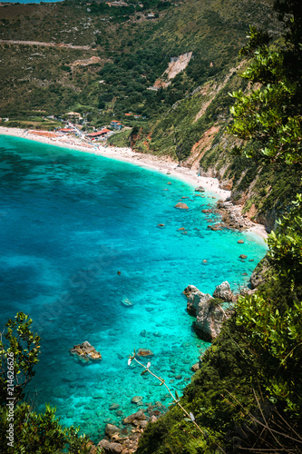 Petani beach on hot sunny summer day. View to Petani bay with transparent and crystal clear blue azure mediterranean sea water in beautiful lagoon, Kefalonia island, Greece