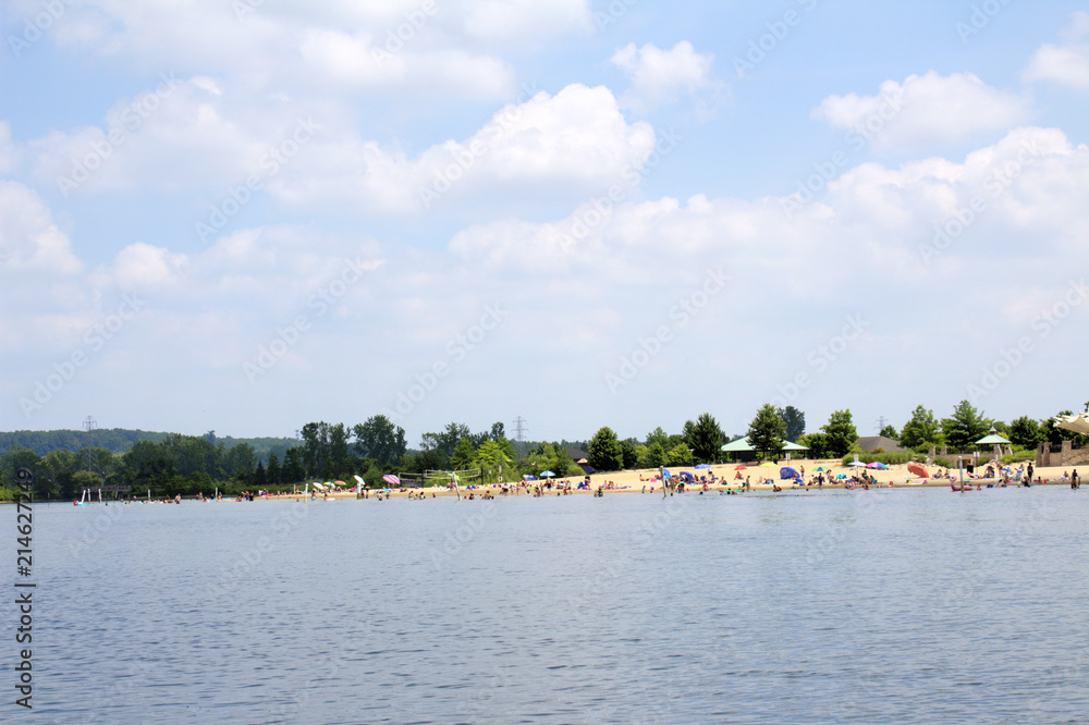 Busy Beach with Swimmers and Sunbathers on Sunny Blue Sky White Cloud Fun Summer Day Busy Beach with Swimmers and Sunbathers on Sunny Blue Sky White Cloud Fun Summer Day