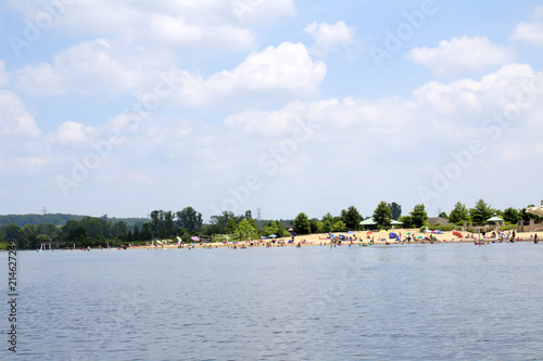 Busy Beach with Swimmers and Sunbathers on Sunny Blue Sky White Cloud Fun Summer Day © Kelsey