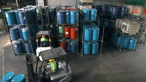 Fork-Lift Carrying 3 Barrels Passing Through Shelves Filled With Barrils 