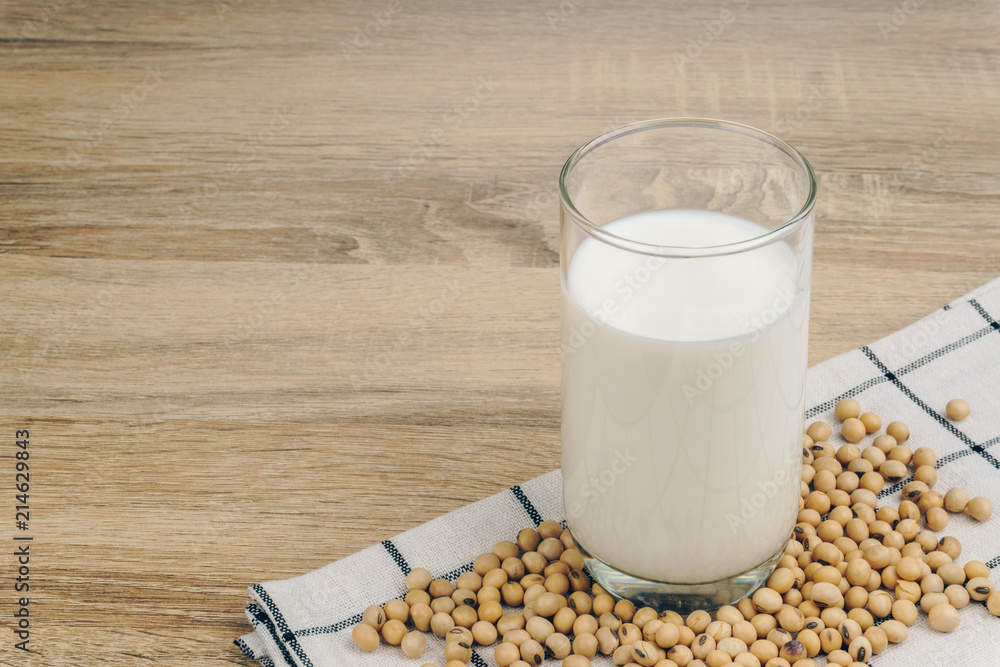 a glass of soy milk and a pile of soybeans on the wooden table. a glass of soy milk and a pile of soybeans on the wooden table.