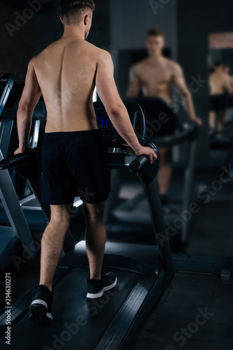 Closeup of a handsome power athletic man bodybuilder doing exercises with dumbbell. Handsome man doing biceps lifting in a gym.Dark background. Unrecognizable, no face portrait