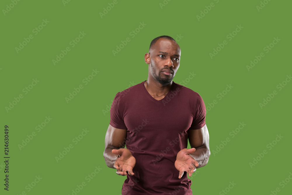 Beautiful male half-length portrait isolated on green studio backgroud. The young emotional surprised man
