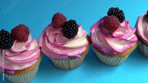 Delicious and appetizing capkake with a pink filling with two berries of blackberries and raspberries on a blue background. Four Cappey Cakes photo