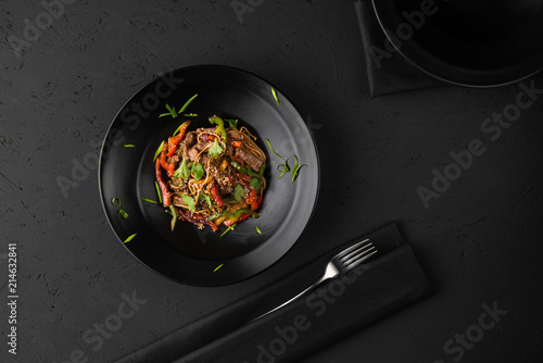 a dish of grilled meat on the black wooden surface, top view