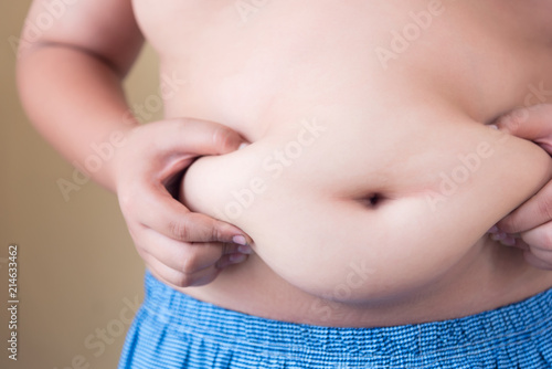 Fat boy with overweight checking out his weight isolated on white background photo