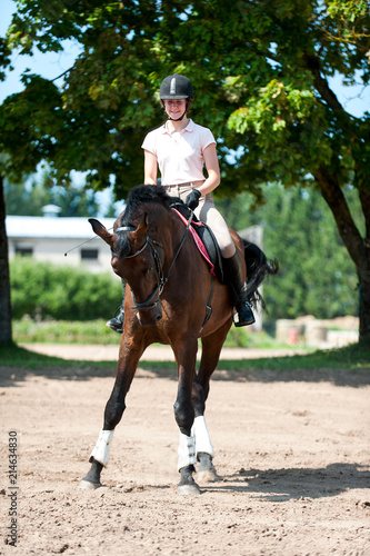 Teenage girl equestrian riding horseback on arena at sport training