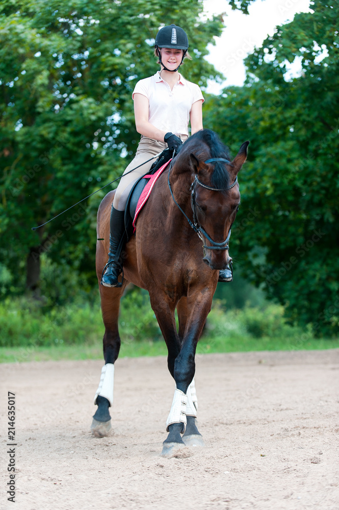Teenage girl equestrian riding horseback on arena at sport training