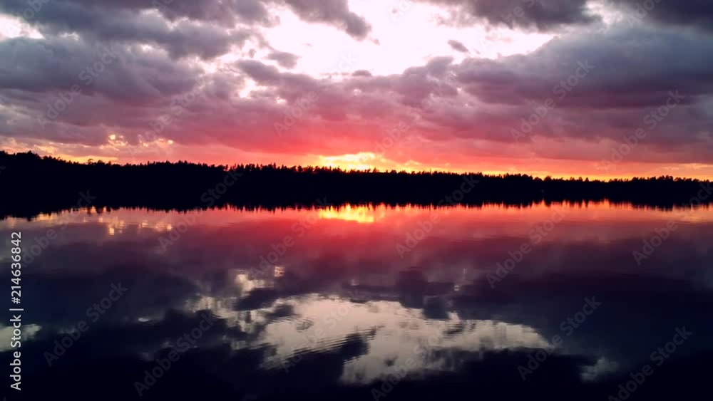 Flying over grass to over an lake with beautiful sunset behind. Flying over grass to over an lake with beautiful sunset behind.