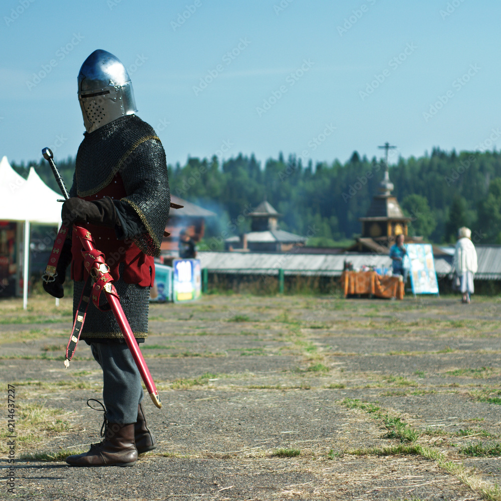 Man in the medieval knight armor with sword gone from the battle reenactment.