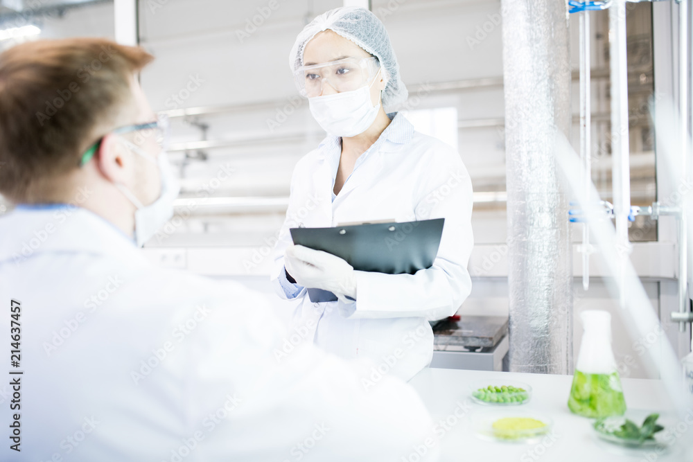 Obraz premium Portrait of two modern young scientists wearing lab coats talking while working in medical laboratory