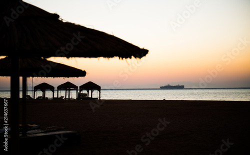 cargo ship at sea horizon through sunrise beach