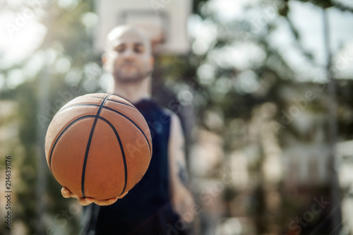 Close up of bald attractive man holding basket ball.