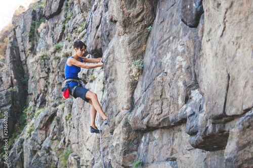 A woman climbs the rock.