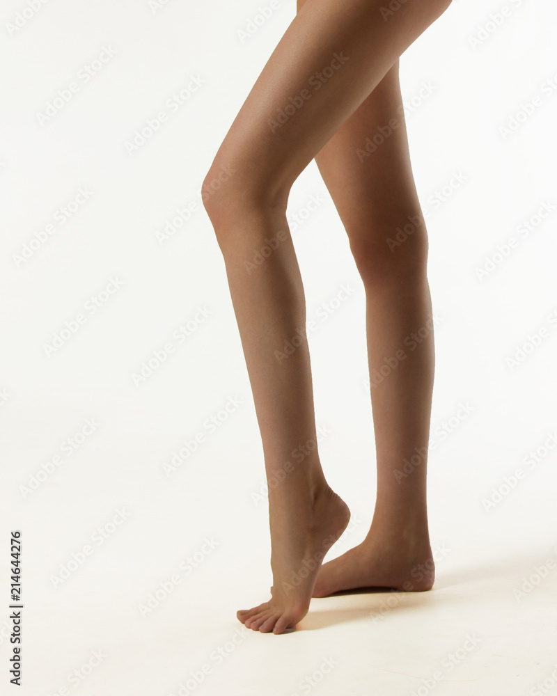 Beautiful long legs of the woman are isolated on a white background.  Suntanned thin legs with clean smooth skin. cream for depilation.  Cosmetology. Sport for legs, diets. Stock Photo | Adobe Stock