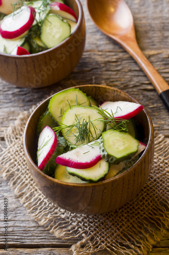 Healthy salad with radishes and cucumbers in a wooden bowl. photo