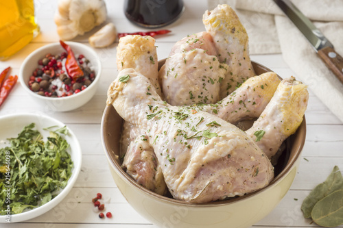 Raw chicken drumstick in marinade with sauce, pepper and herbs. Selective focus.