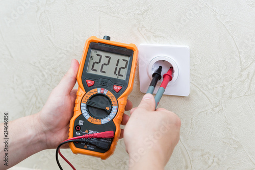 Close-up of man measuring and cheking power supply voltage with digital multimeter