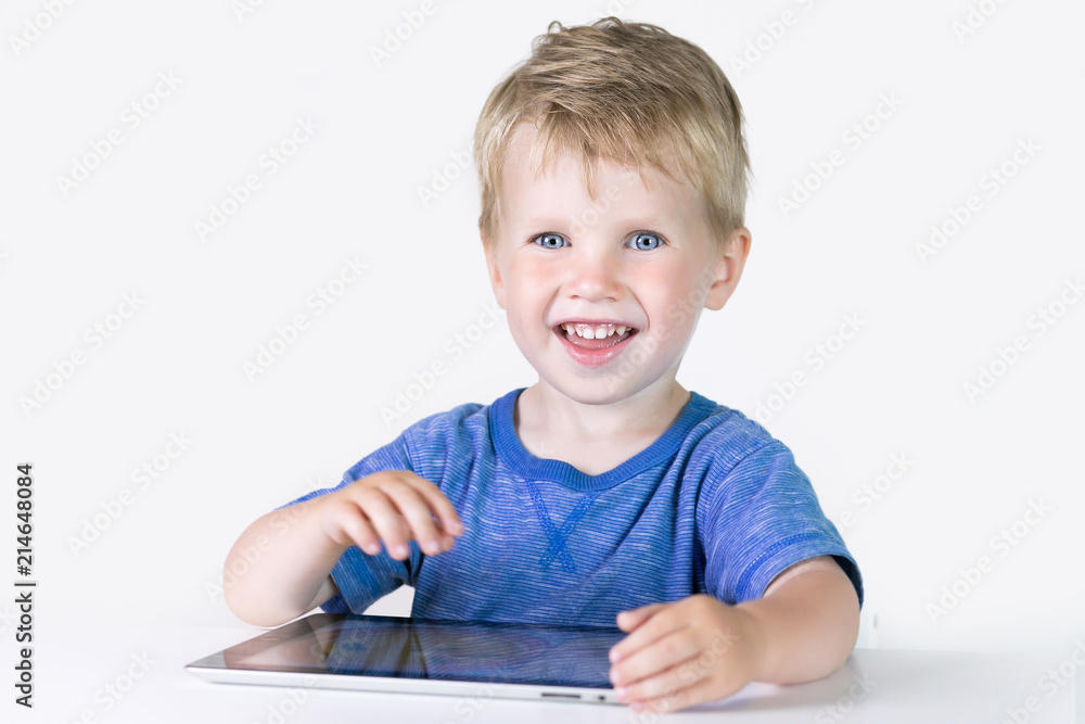 Three years old little kid boy playing children educational or developing games or on the tablet computer at home on white background Three years old little kid boy playing children educational or developing games or on the tablet computer at home on white background