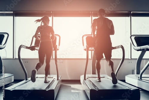 Bearded Man and Young Woman on Treadmills in Gym.
