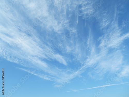 Blue sky with white feathery clouds in sunny day. Cirrus clouds as beautiful weather background