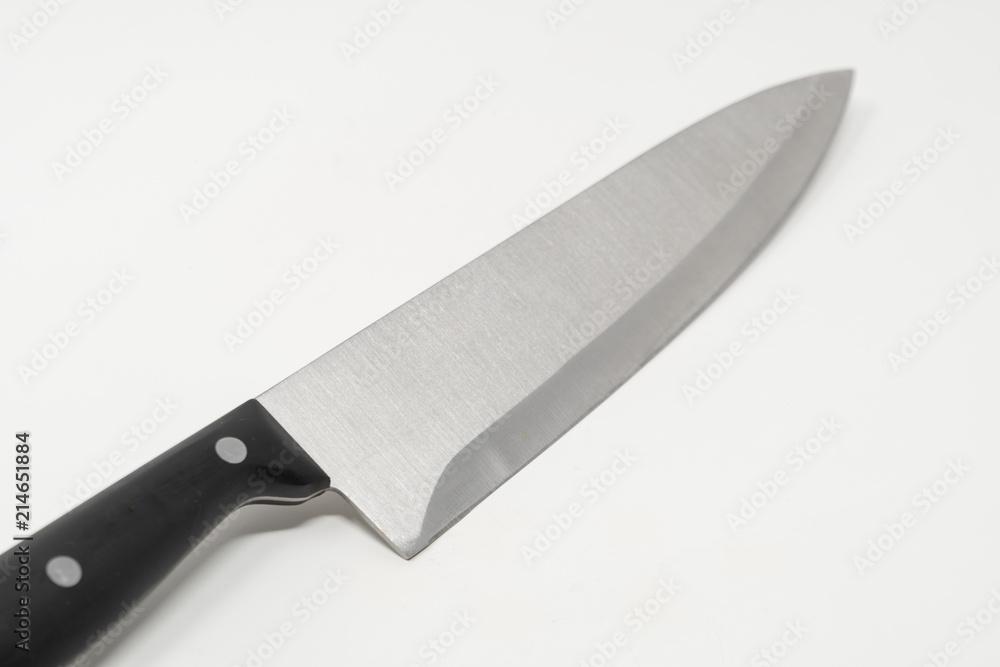 An angled stainless steel kitchen knife set against a white background An angled stainless steel kitchen knife set against a white background