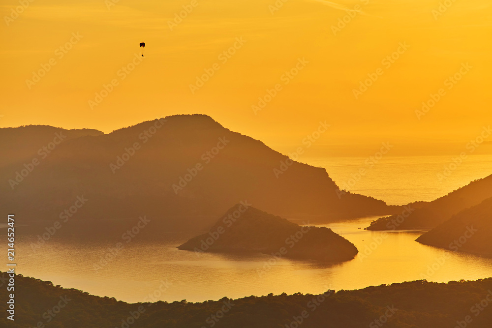 An unidentified paraglider flying at sunset over Blue lagoon in Oludeniz,
