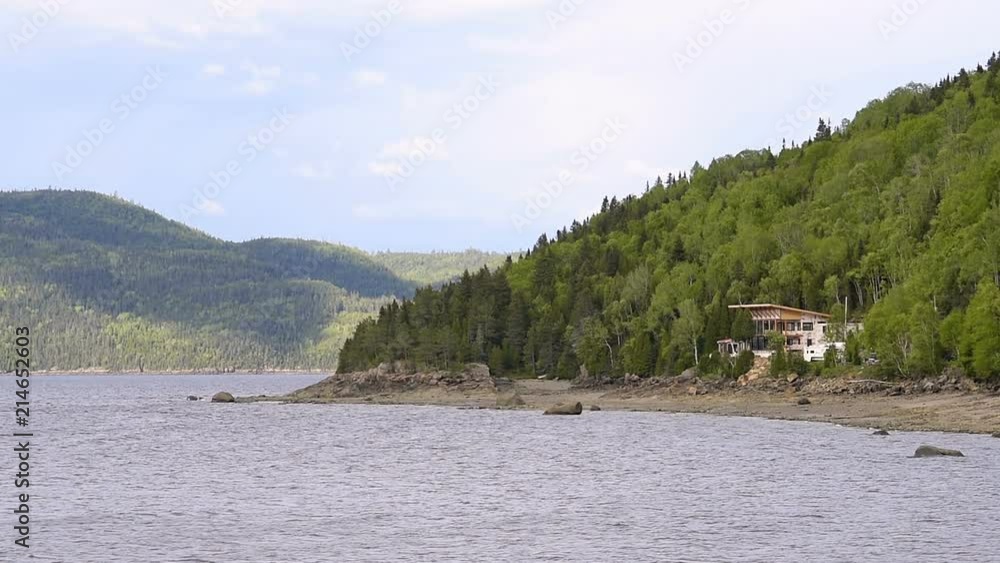 Fjord coast, nature near Saguenay river, cliffs, tree forest, mountains, house, vacation home, clouds, cloudy sky in Quebec, Canada Fjord coast, nature near Saguenay river, cliffs, tree forest, mountains, house, vacation home, clouds, cloudy sky in Quebec, Canada