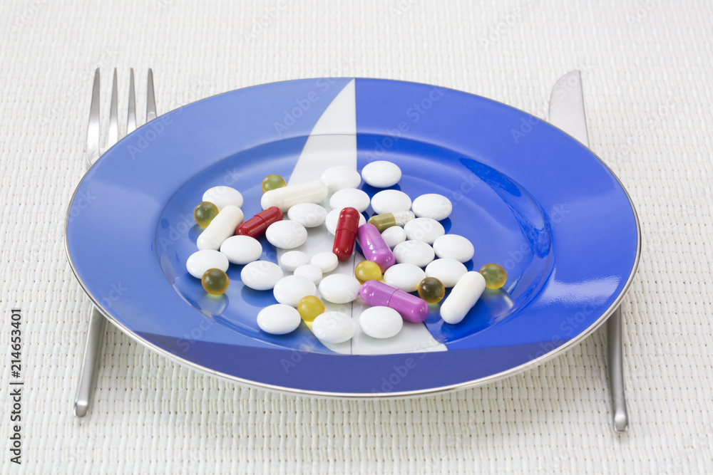 Drug consumption concept. Laid table with drugs on blue dish and cutlery next to the plate Drug consumption concept. Laid table with drugs on blue dish and cutlery next to the plate