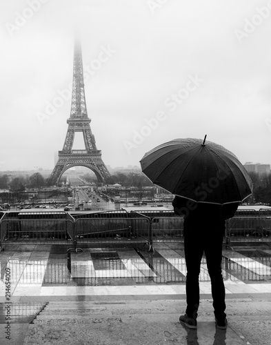 a man with an umbrella near the eifell tower photo