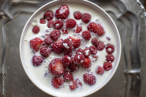 Raspberry with milk in a white bowl