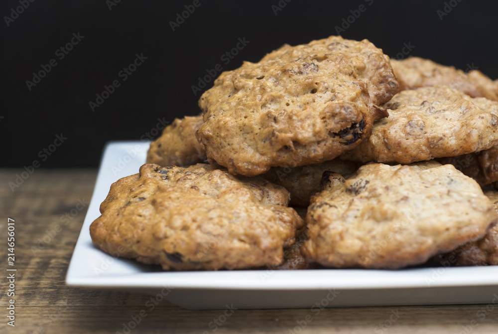 Homemade oat meal cookies in white square plate, on wooden board and Black background. Sweet dessert snack, Healthy Food. Copy space. Homemade oat meal cookies in white square plate, on wooden board and Black background. Sweet dessert snack, Healthy Food. Copy space.