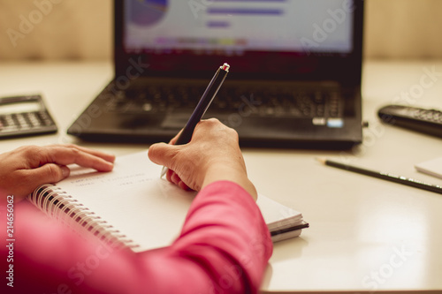 Close-up photograph of woman's hands making notes on notepad, work folder
