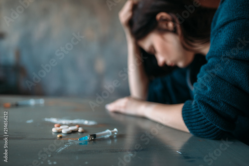 Drug addict sitting at the table with narcotics photo