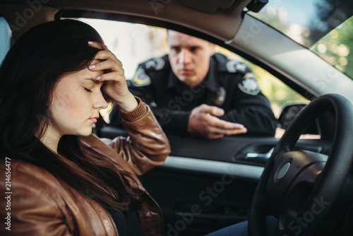 Male cop in uniform check female driver on road