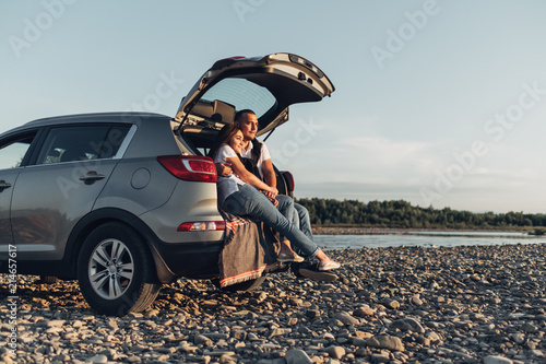 Tableau sur toile Happy Couple on Roadtrip into the Sunset in SUV Car