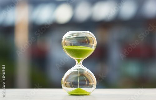 Close-up, hourglass with green sand on a blurred background photo