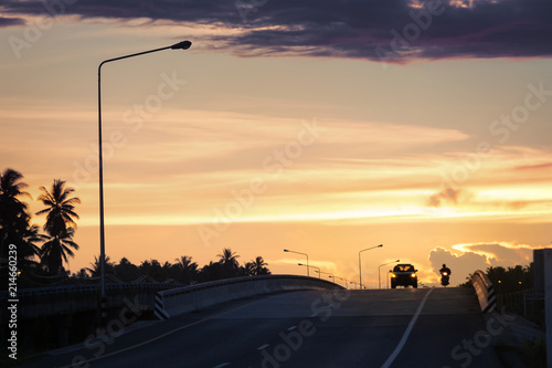 Car on the road outside the city at sunset and sky with clouds