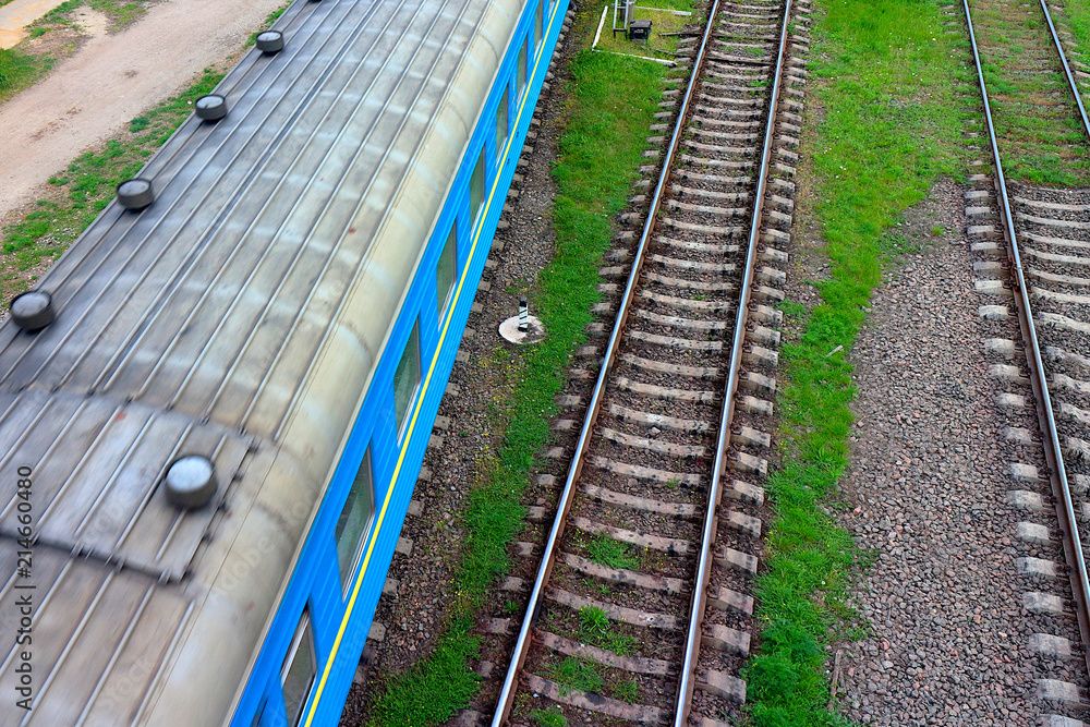 Wagon of a moving train on railroad. Rural railway station on cloudy day. Top view