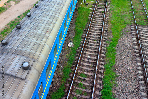 Wagon of a moving train on railroad. Rural railway station on cloudy day. Top view